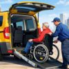 Wheelchair taxi with ramp assisting passenger into accessible vehicle